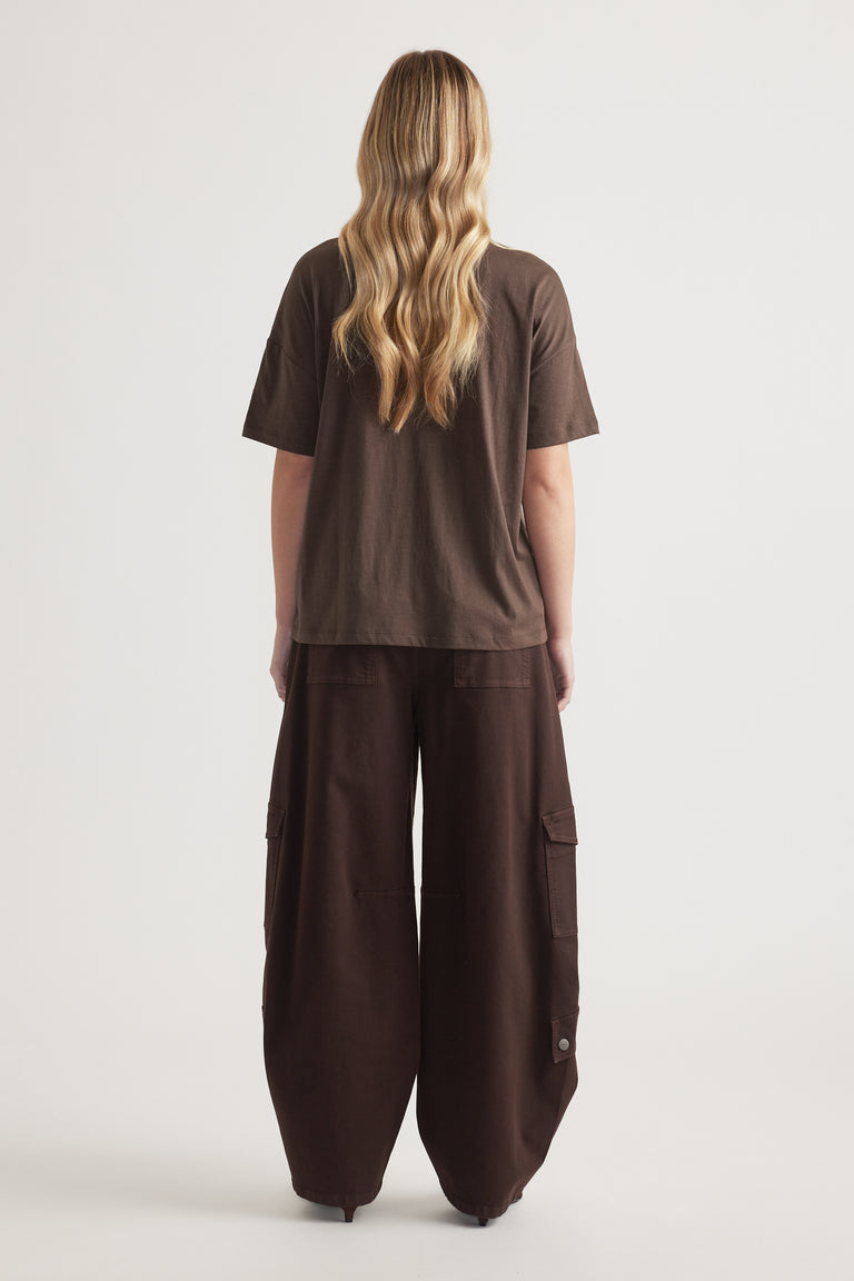 Back view of woman wearing a relaxed brown short sleeve tee with wide-leg cargo pants