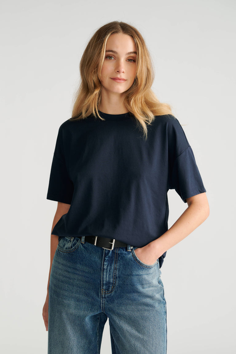 Woman wearing a relaxed fit navy short sleeve tee paired with high-rise classic blue denim jeans and a black belt.