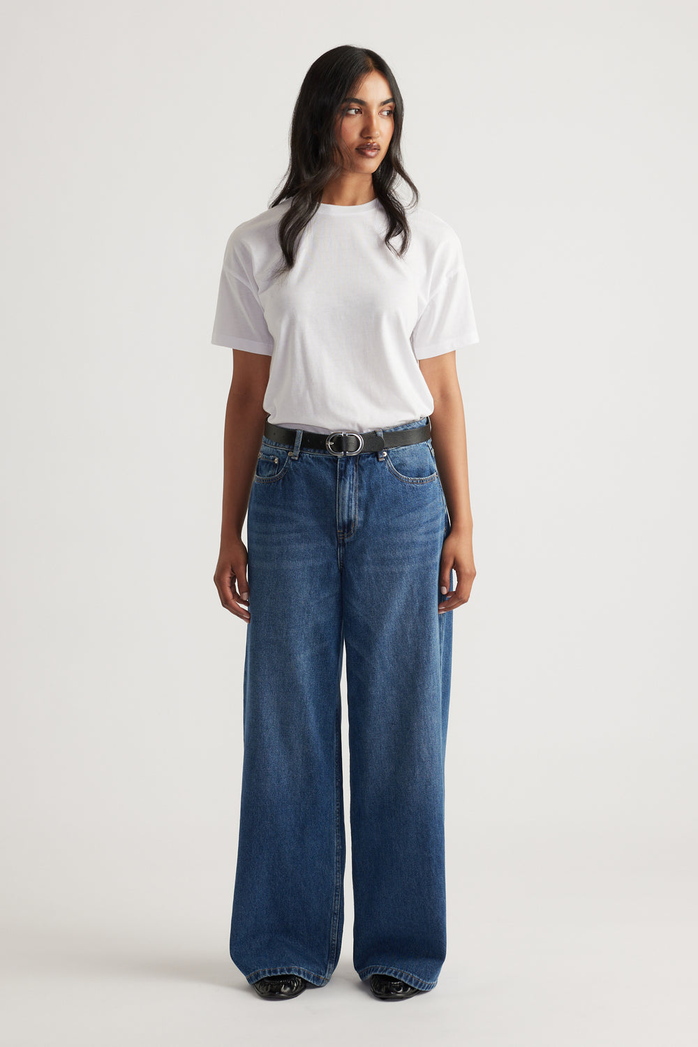 Woman wearing a classic white short sleeve tee tucked into high-waisted wide-leg blue denim jeans with a black belt