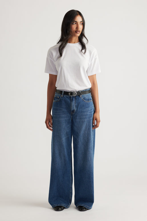 Woman wearing a classic white short sleeve tee tucked into high-waisted wide-leg blue denim jeans with a black belt