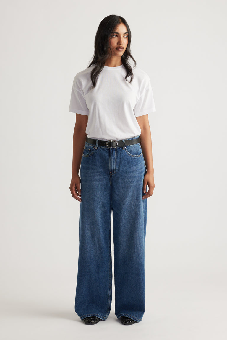 Woman wearing a classic white short sleeve tee tucked into high-waisted wide-leg blue denim jeans with a black belt