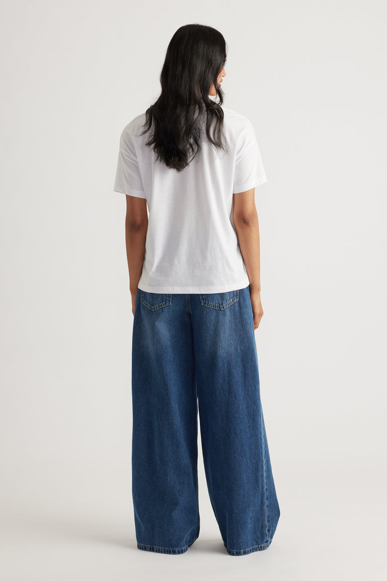 Person wearing a relaxed white short sleeve tee paired with wide-leg blue denim pants for a casual look