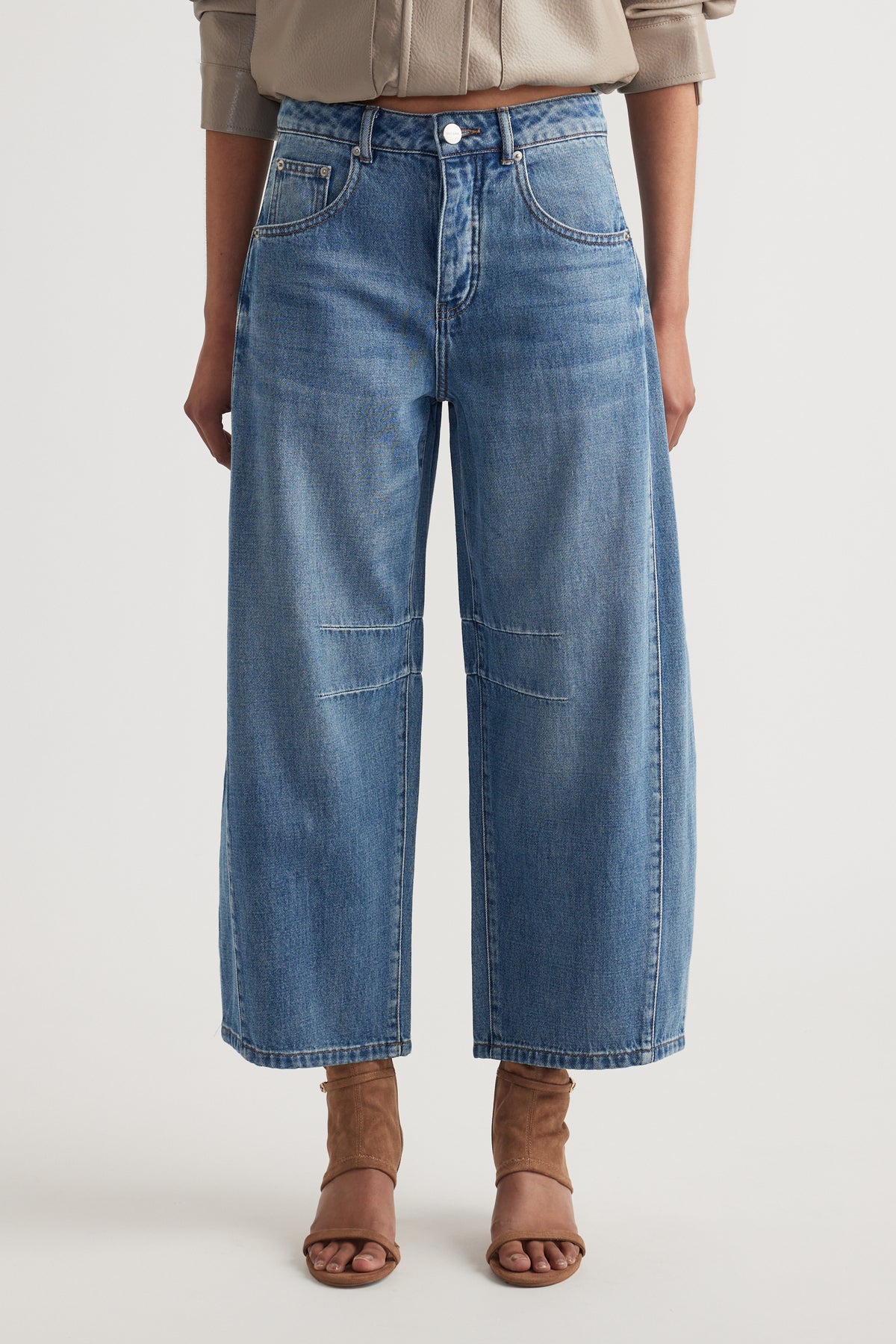Relaxed fit blue denim jeans with wide legs and knee seam detail paired with tan open-toe heels