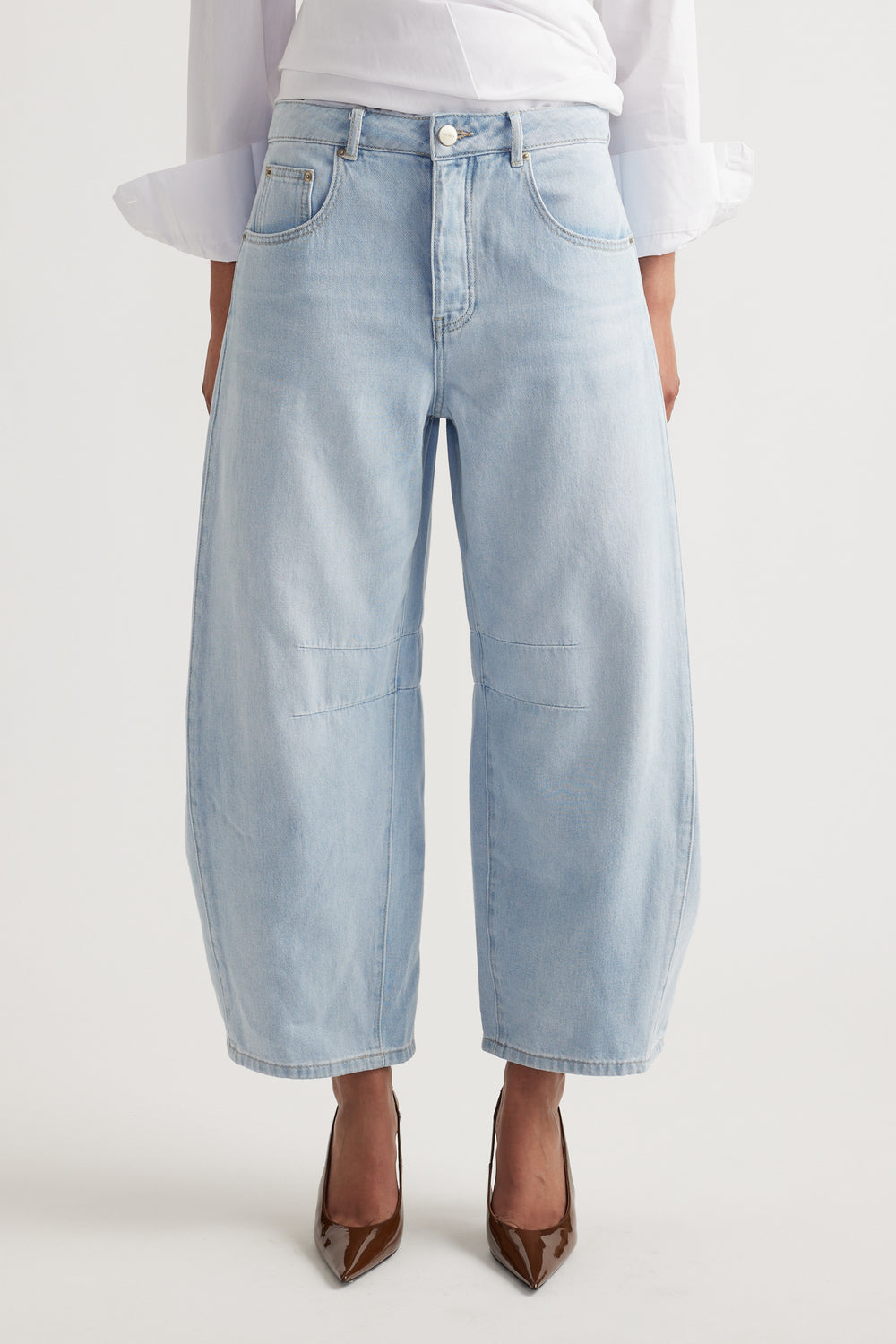 Light wash wide-leg denim jeans with relaxed fit and subtle knee seam detailing, styled with brown heels.