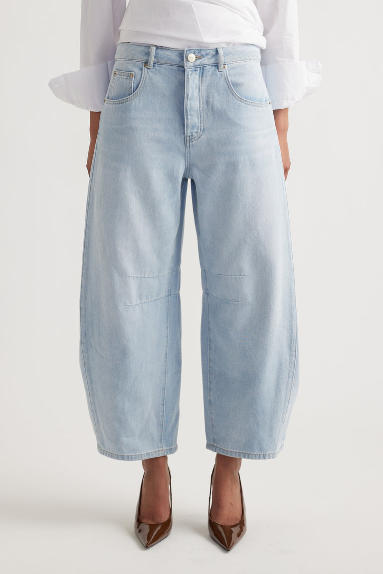 Light wash wide-leg denim jeans with relaxed fit and subtle knee seam detailing, styled with brown heels.