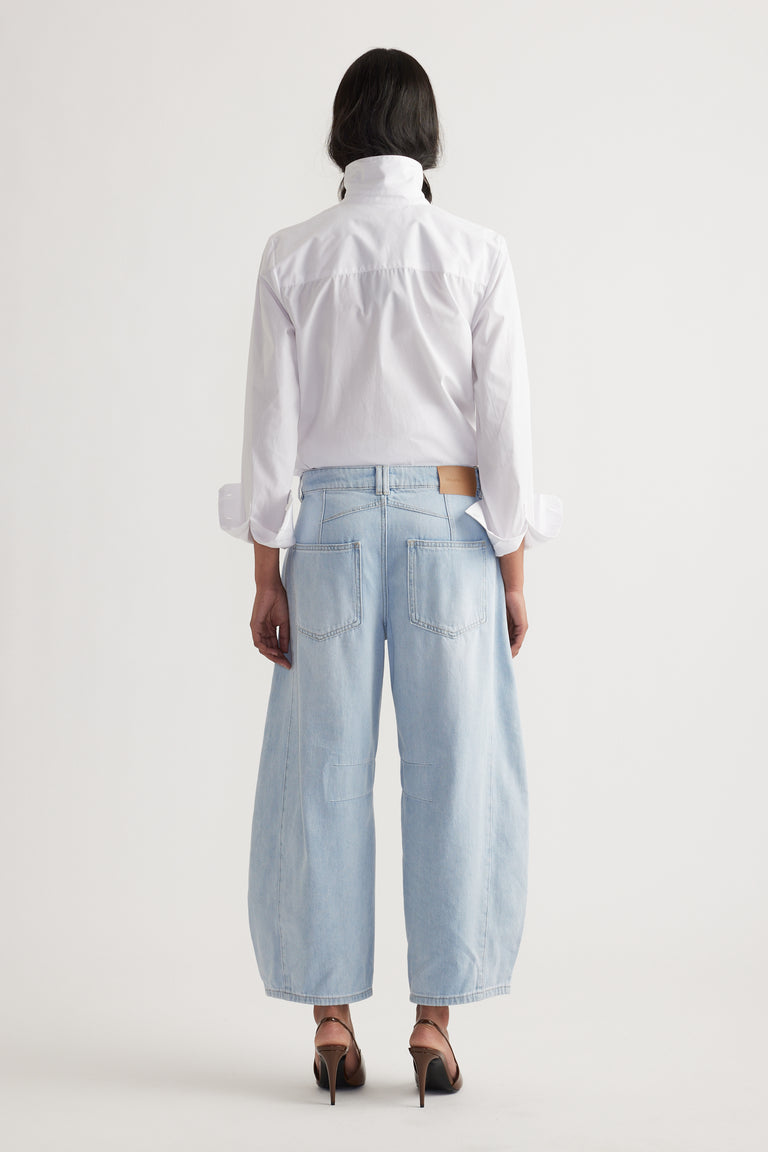 Back view of relaxed light wash wide-leg jeans paired with a crisp white shirt and heels in soft lighting