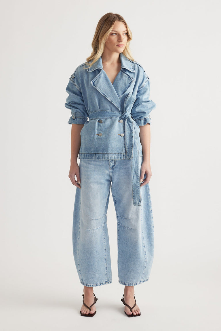 Woman wearing a light wash denim belted jacket paired with high-rise wide-leg denim jeans and black heeled sandals