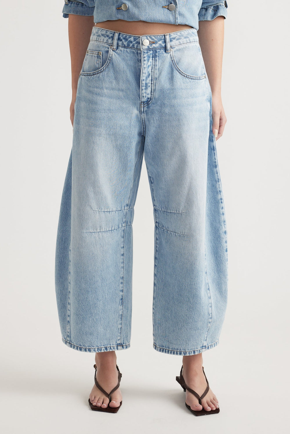 Woman wearing light wash high-rise wide leg cropped jeans styled with black thong sandals