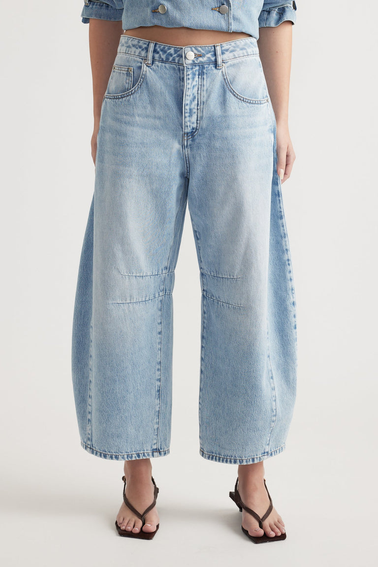 Woman wearing light wash high-rise wide leg cropped jeans styled with black thong sandals