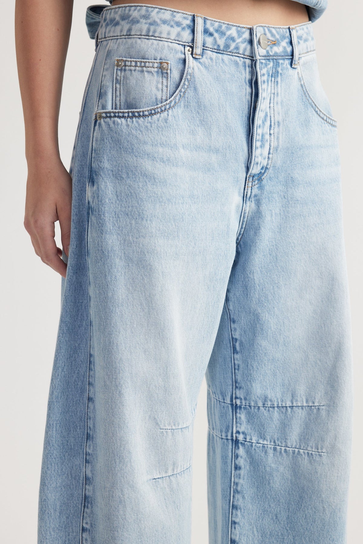 Light wash high-rise denim jeans with barrel leg, front and back pockets, and button fly fastening