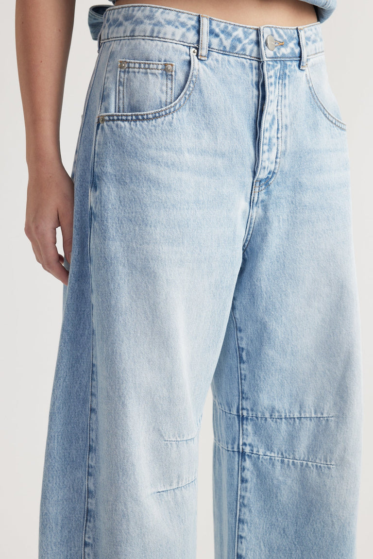 Light wash high-rise denim jeans with barrel leg, front and back pockets, and button fly fastening