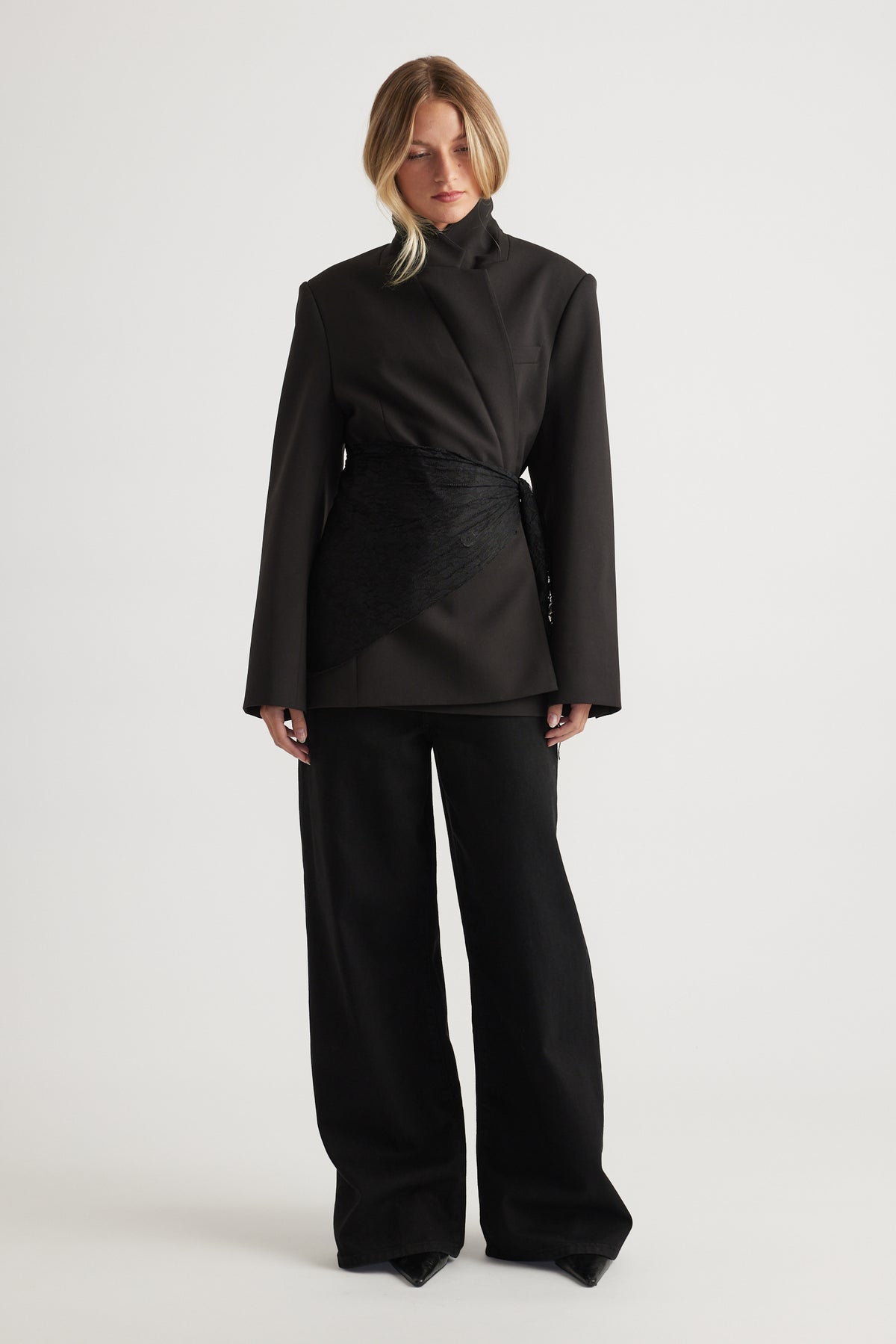 Woman wearing black oversized blazer styled with Penny Lace Scarf wrapped at the waist and wide-leg pants by DECJUBA.