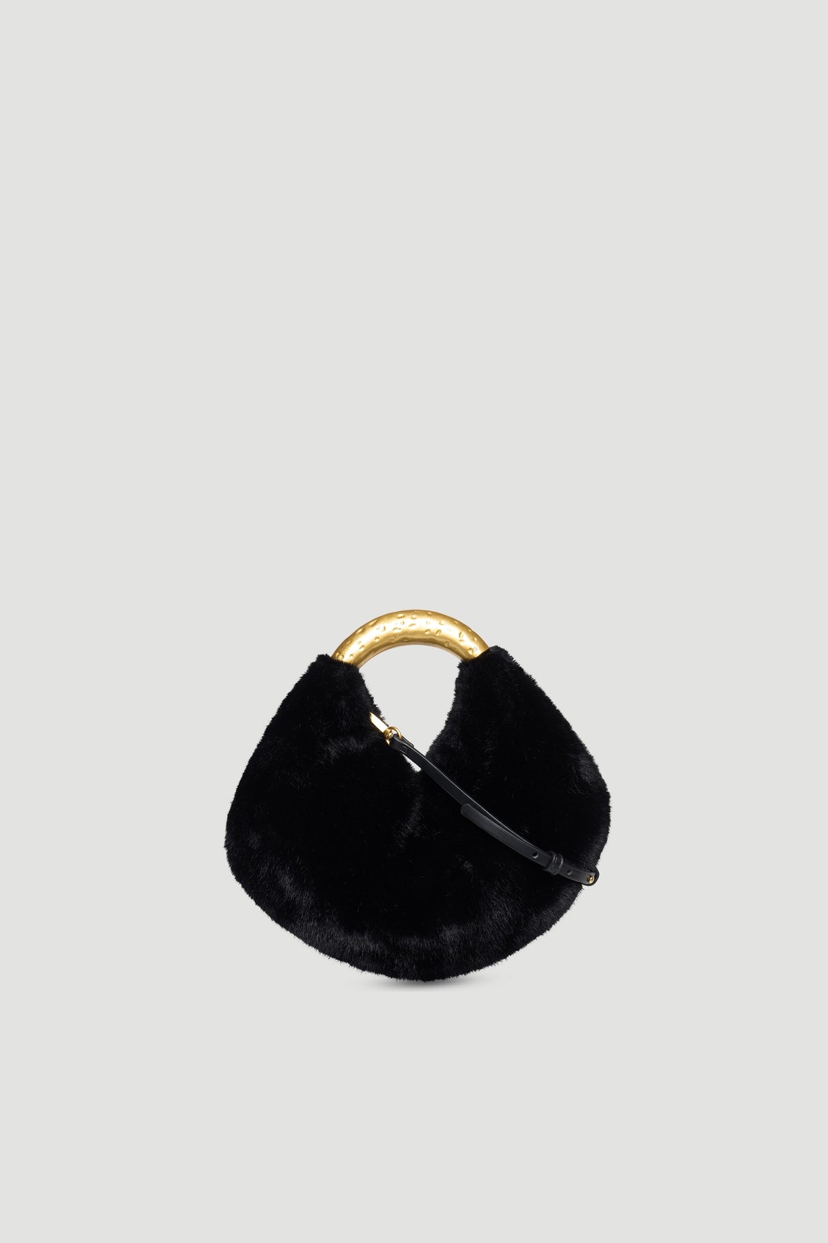 Black faux fur handbag with curved hammered gold metal handle and detachable slim black strap on plain background
