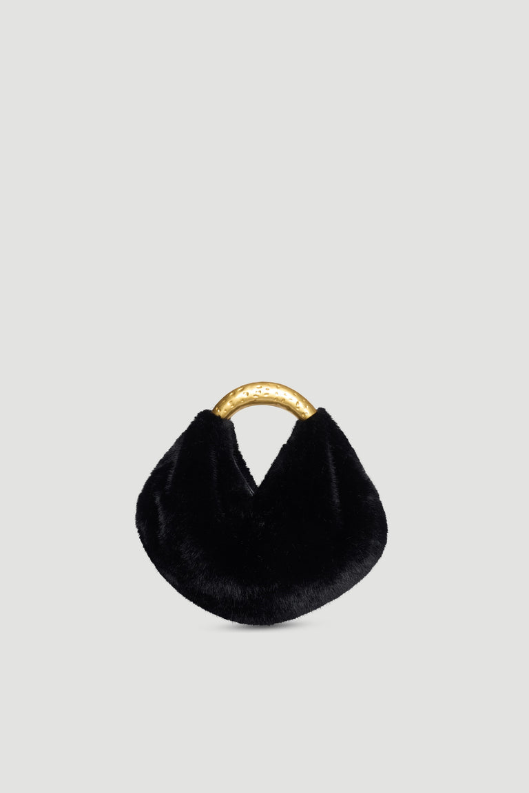 Small black faux fur bag with curved hammered gold metal handle and magnetic snap closure on plain background