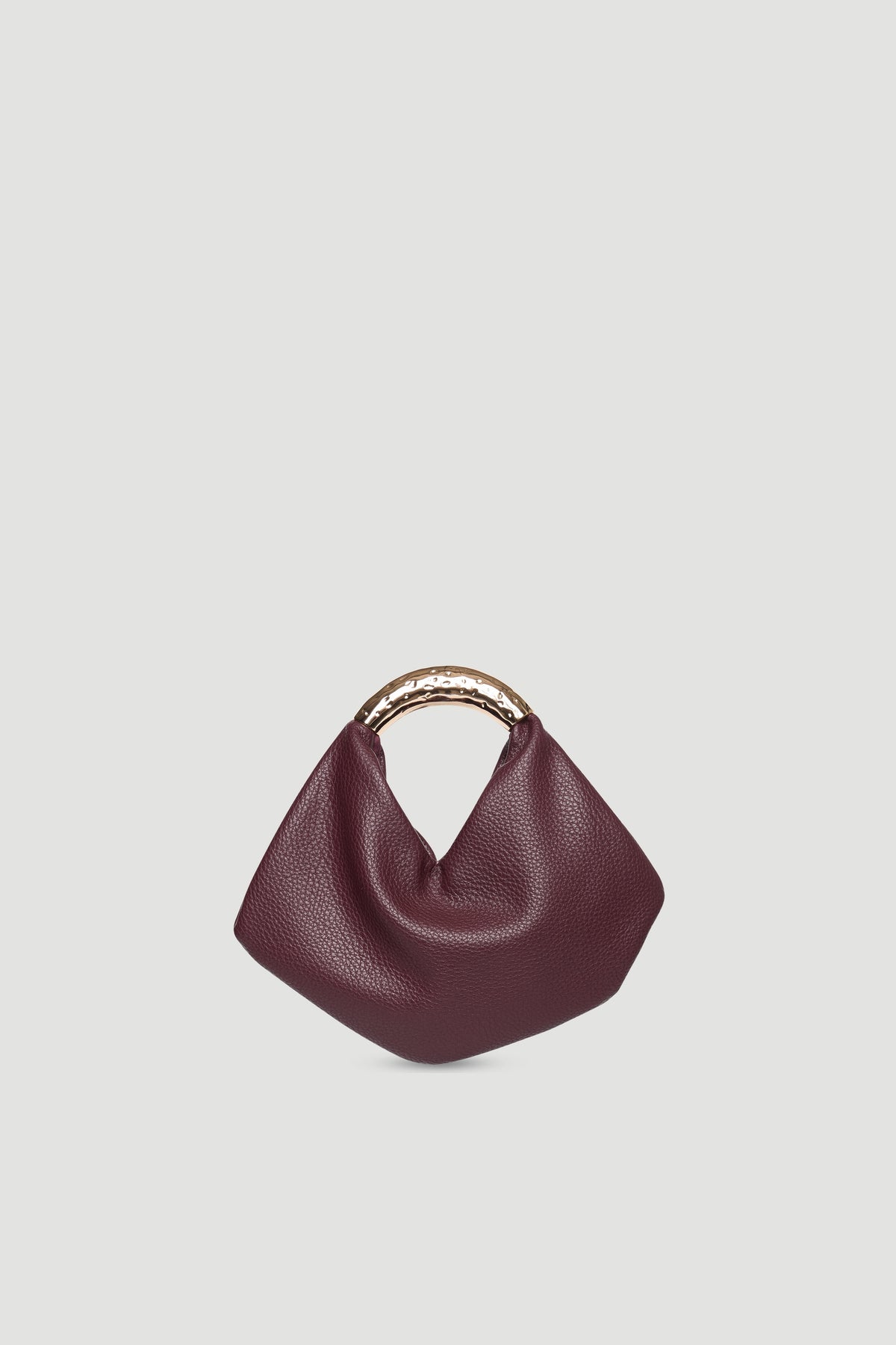 Small soft pebble bag in deep burgundy with hammered gold metal handle and magnetic snap closure against neutral background