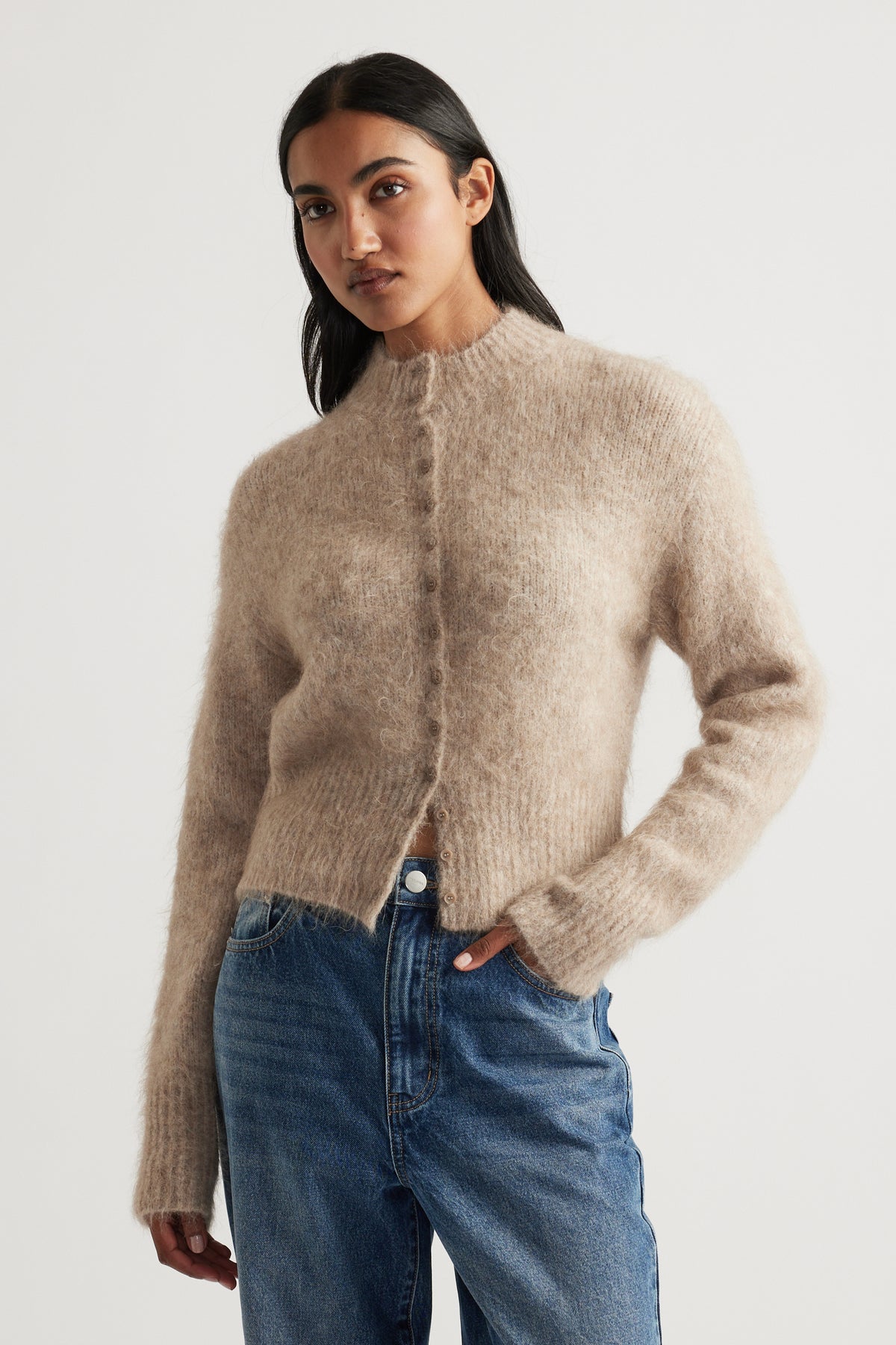 Woman wearing a soft stone-coloured alpaca blend cardigan with a cozy texture paired with relaxed blue jeans