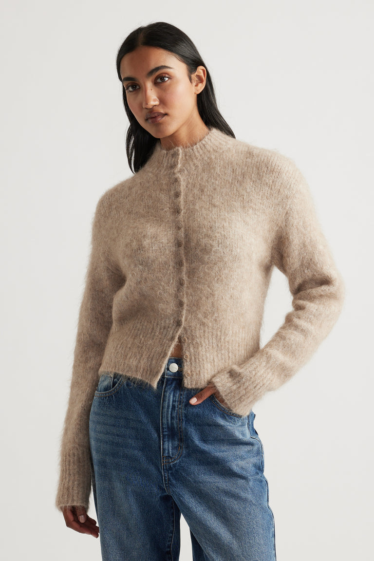 Woman wearing a soft stone-coloured alpaca blend cardigan with a cozy texture paired with relaxed blue jeans