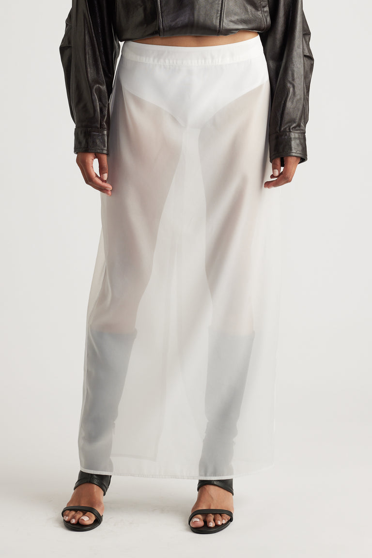 Sheer white organza maxi skirt styled with black leather long-sleeve top and open-toe black sandals