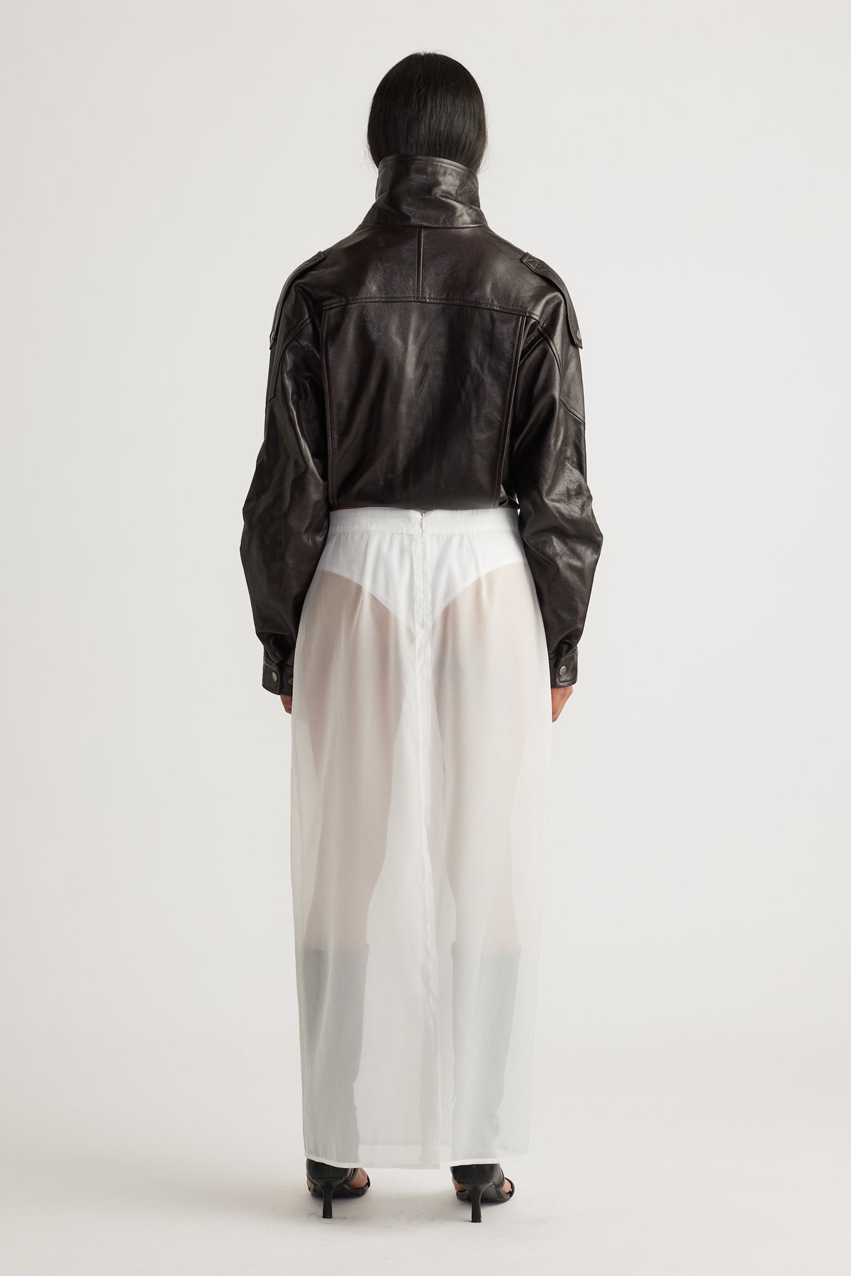 Back view of a sheer ivory organza maxi skirt layered over fitted shorts, styled with a cropped black leather jacket