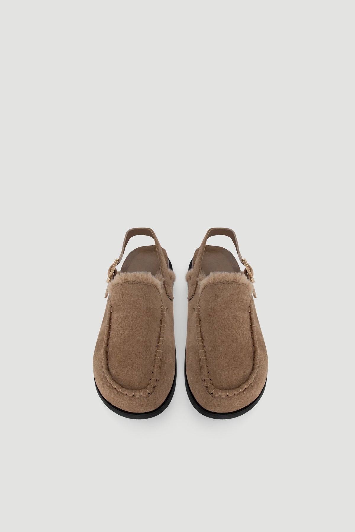 Pair of tan suede slingback shoes featuring a soft shearling trim and black sole, offering cozy casual style.