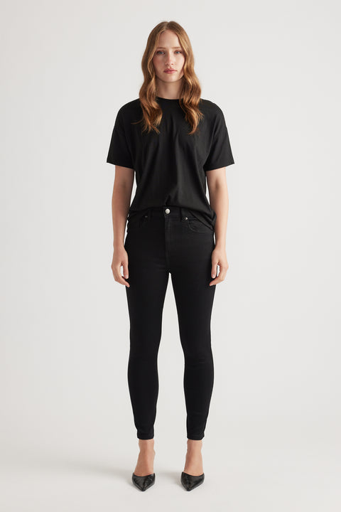 Woman wearing black skinny denim jeans paired with a relaxed black tee and pointed black heels for a sleek look