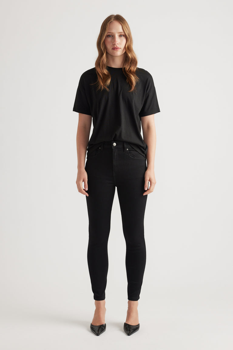 Woman wearing black skinny denim jeans paired with a relaxed black tee and pointed black heels for a sleek look