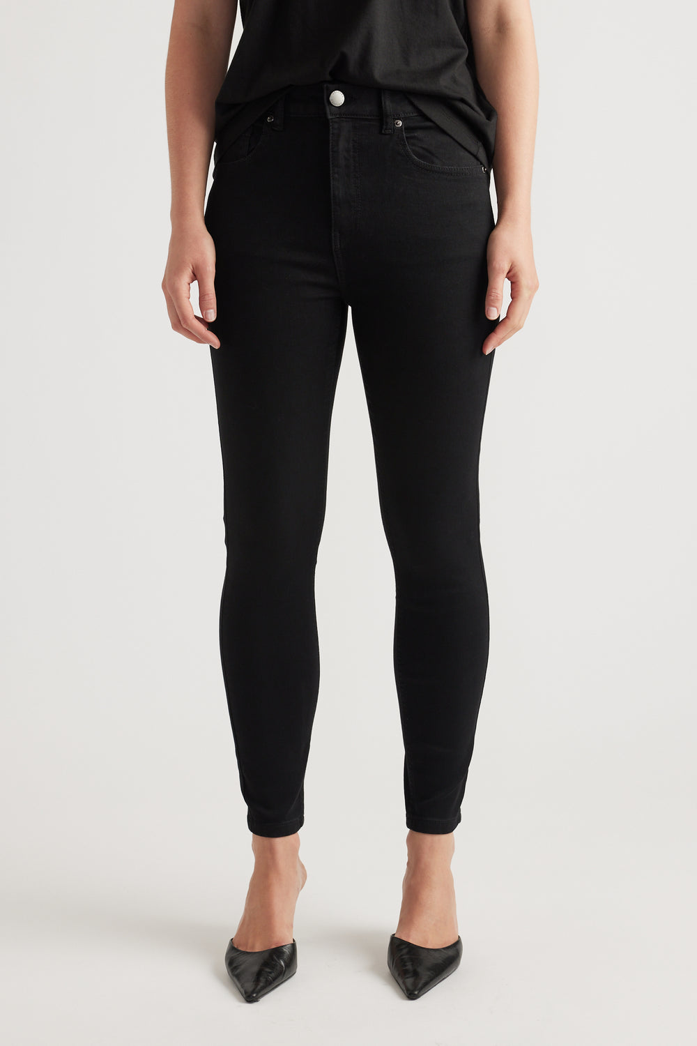Slim fit black denim jeans with a high waist and classic five-pocket styling, paired with pointed black heels