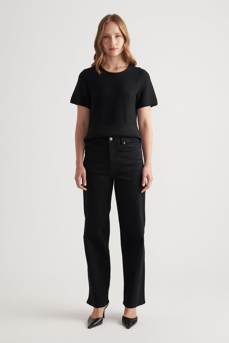 Woman wearing black stretch straight jeans paired with a simple black short-sleeve knit top and pointed heels