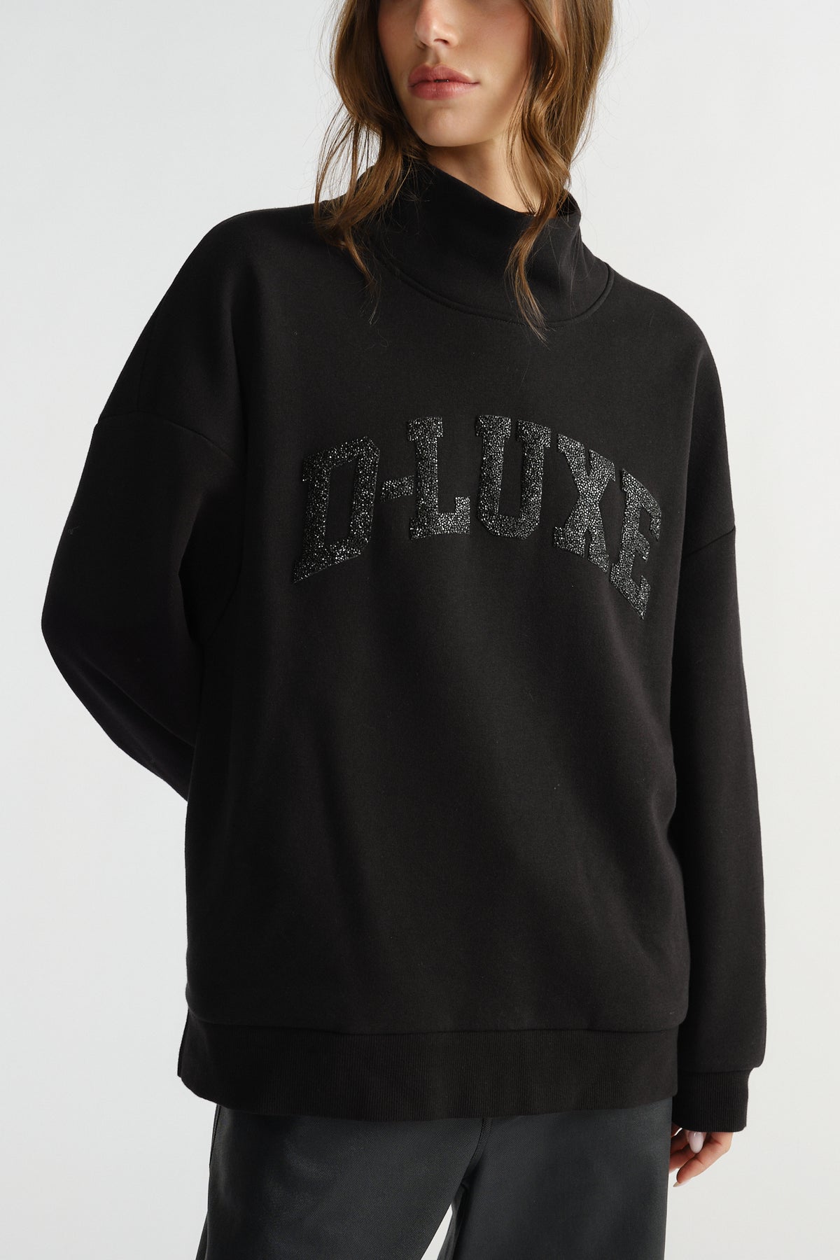 Woman wearing a black mock neck sweat with subtle sparkle lettering for a stylish, comfortable everyday look