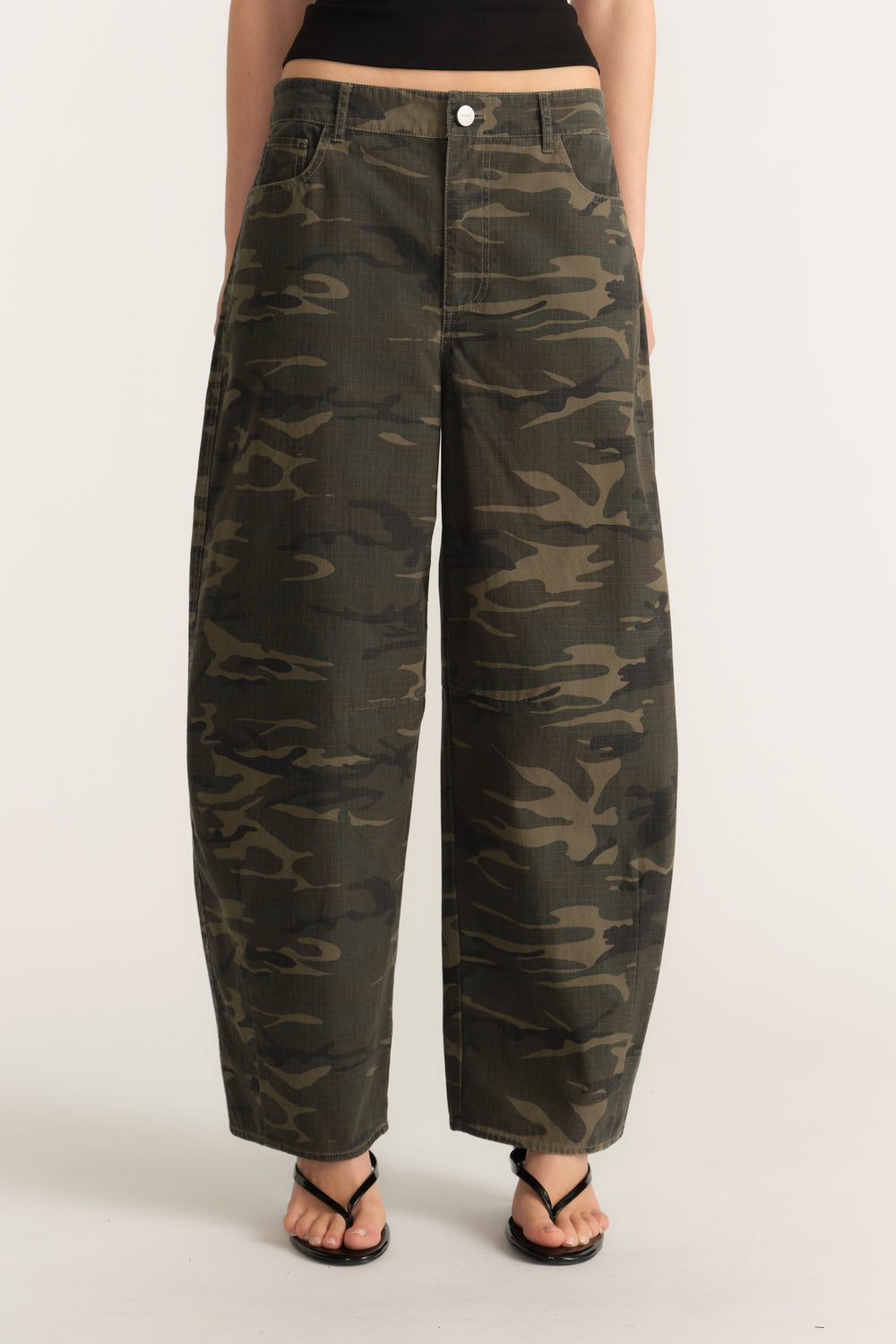 Woman wearing mid rise camouflage barrel leg pants with a zip fly and ankle length fit