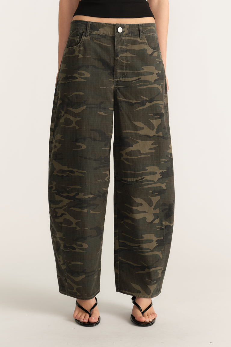 Woman wearing mid rise camouflage barrel leg pants with a zip fly and ankle length fit