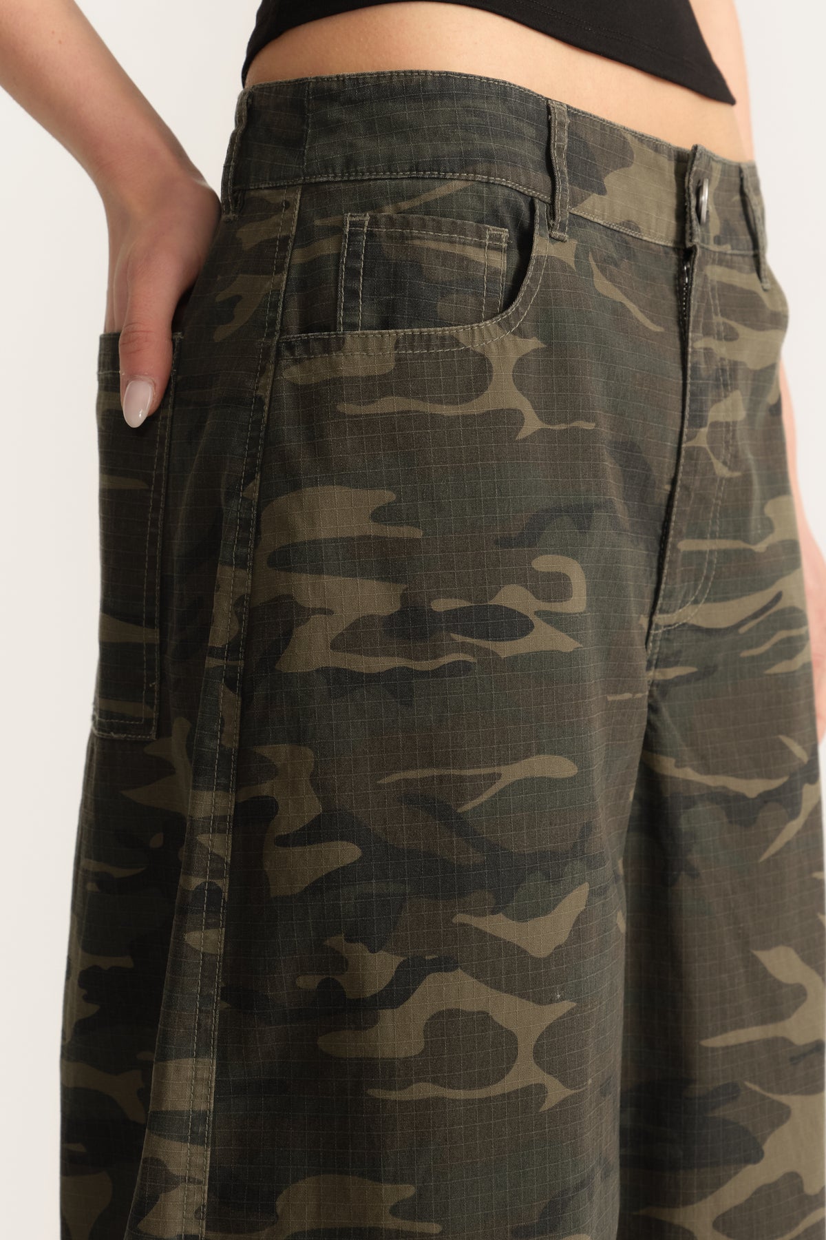 Woman wearing camo barrel leg pants with a mid rise waist and ankle length fit