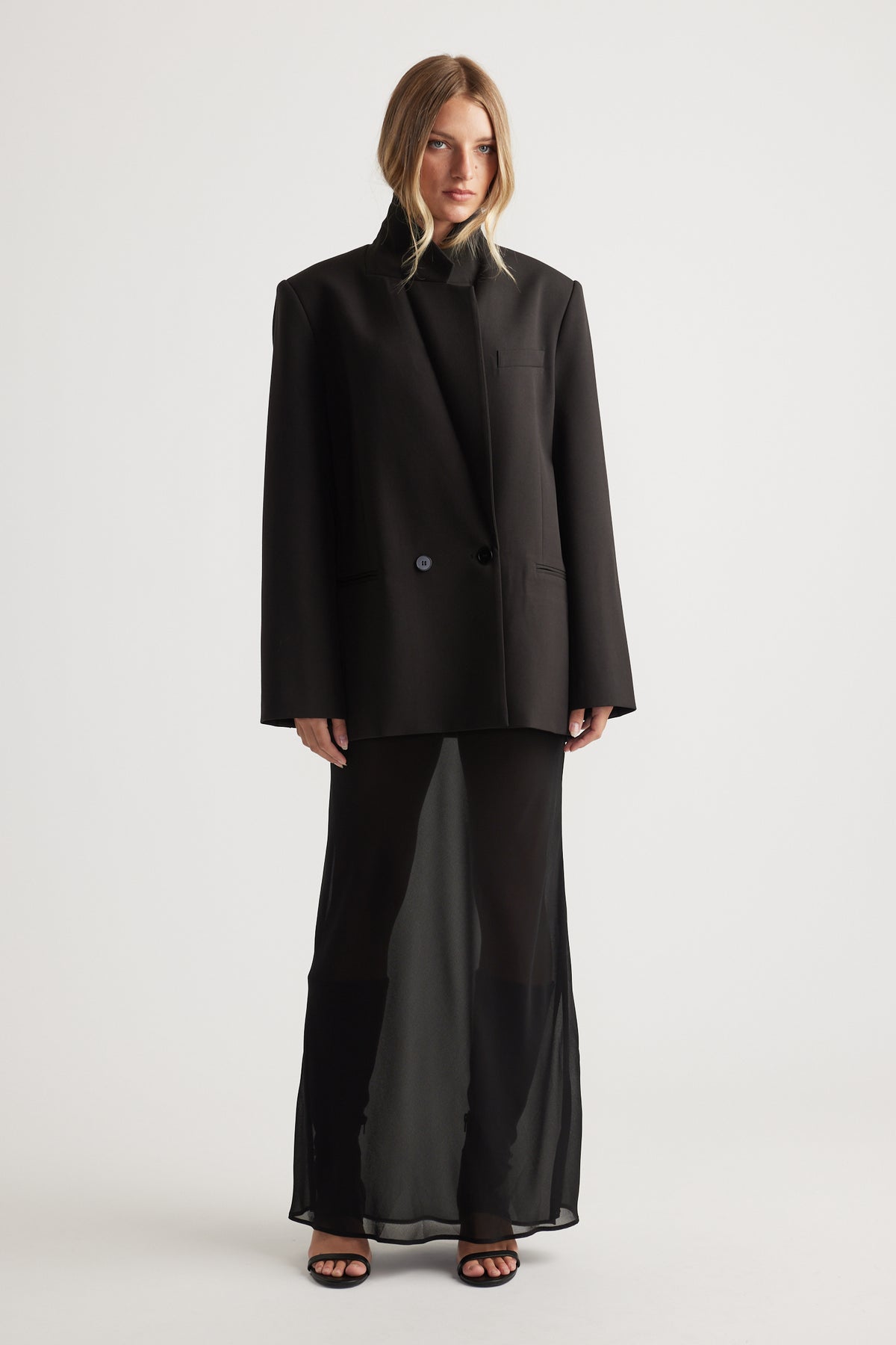 Model wearing Faye Sheer Maxi Skirt in black styling a relaxed black blazer by DECJUBA Australian fashion brand