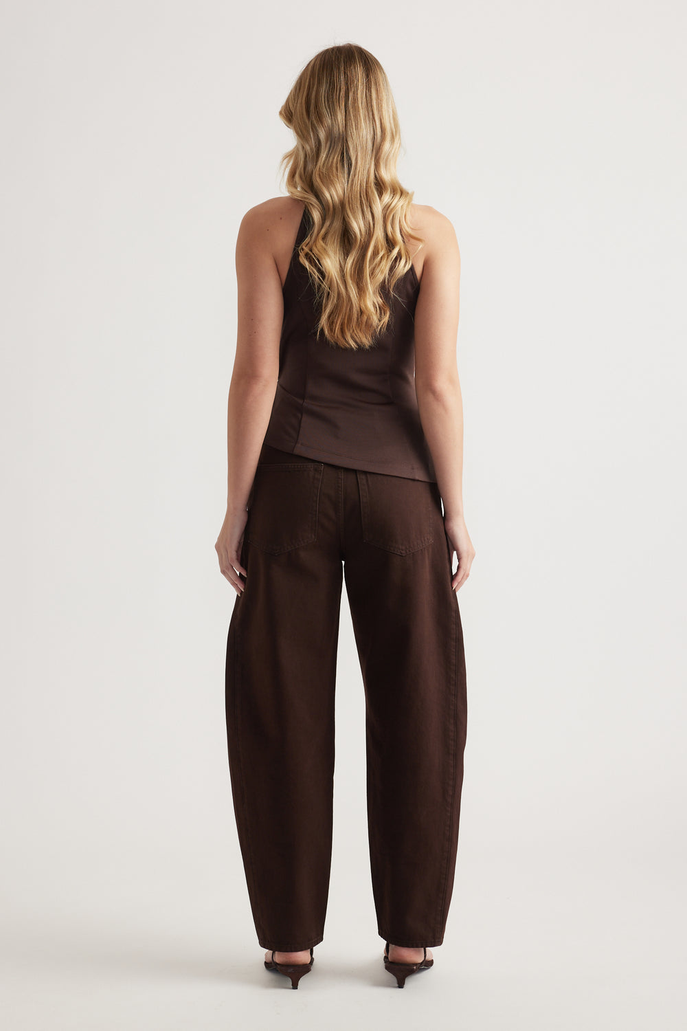 Back view of woman in a brown halter top with matching wide leg pants and heels