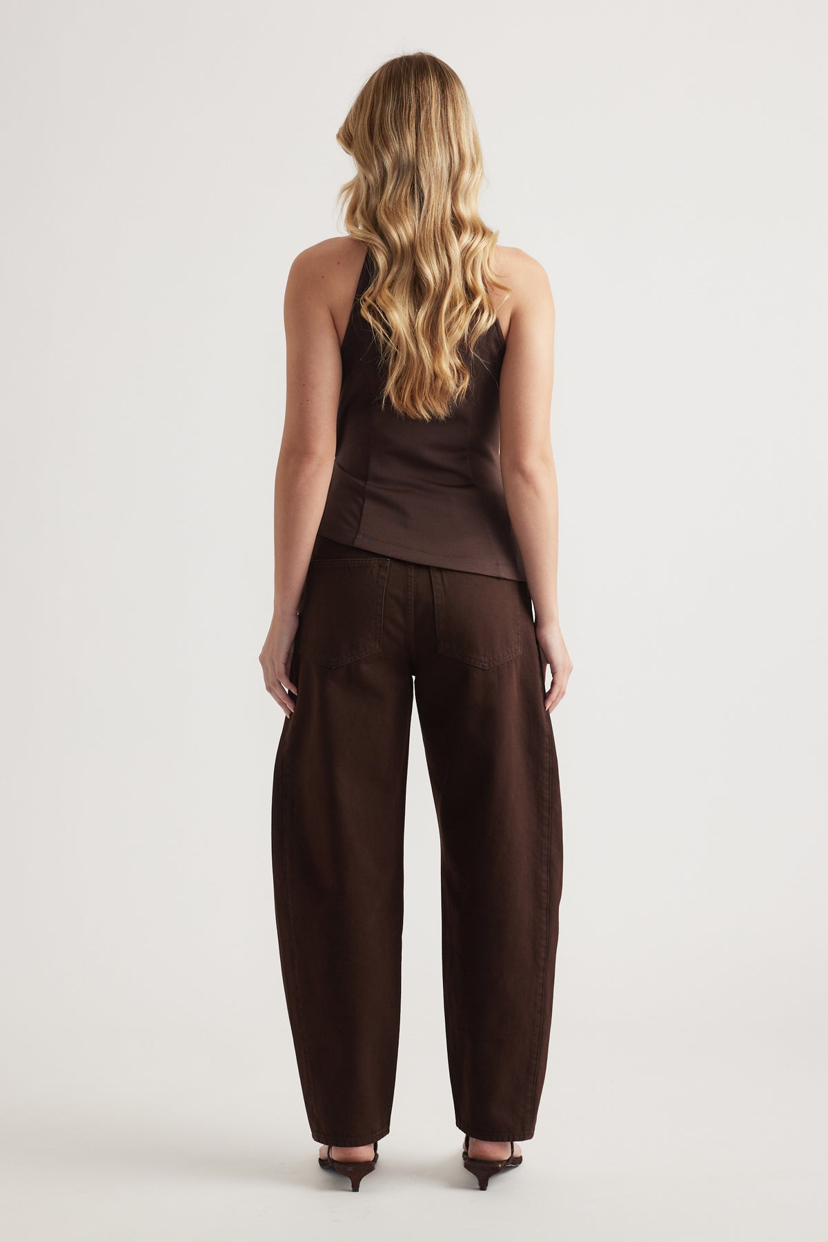 Back view of woman in a brown halter top with matching wide leg pants and heels