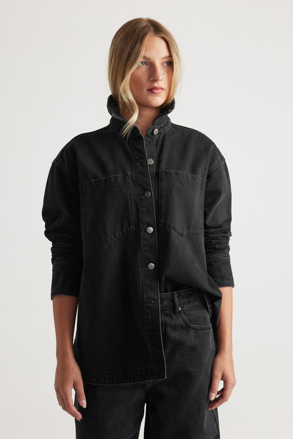 Woman wearing black denim shirt with snap buttons and chest pockets paired with black denim jeans for a modern casual look