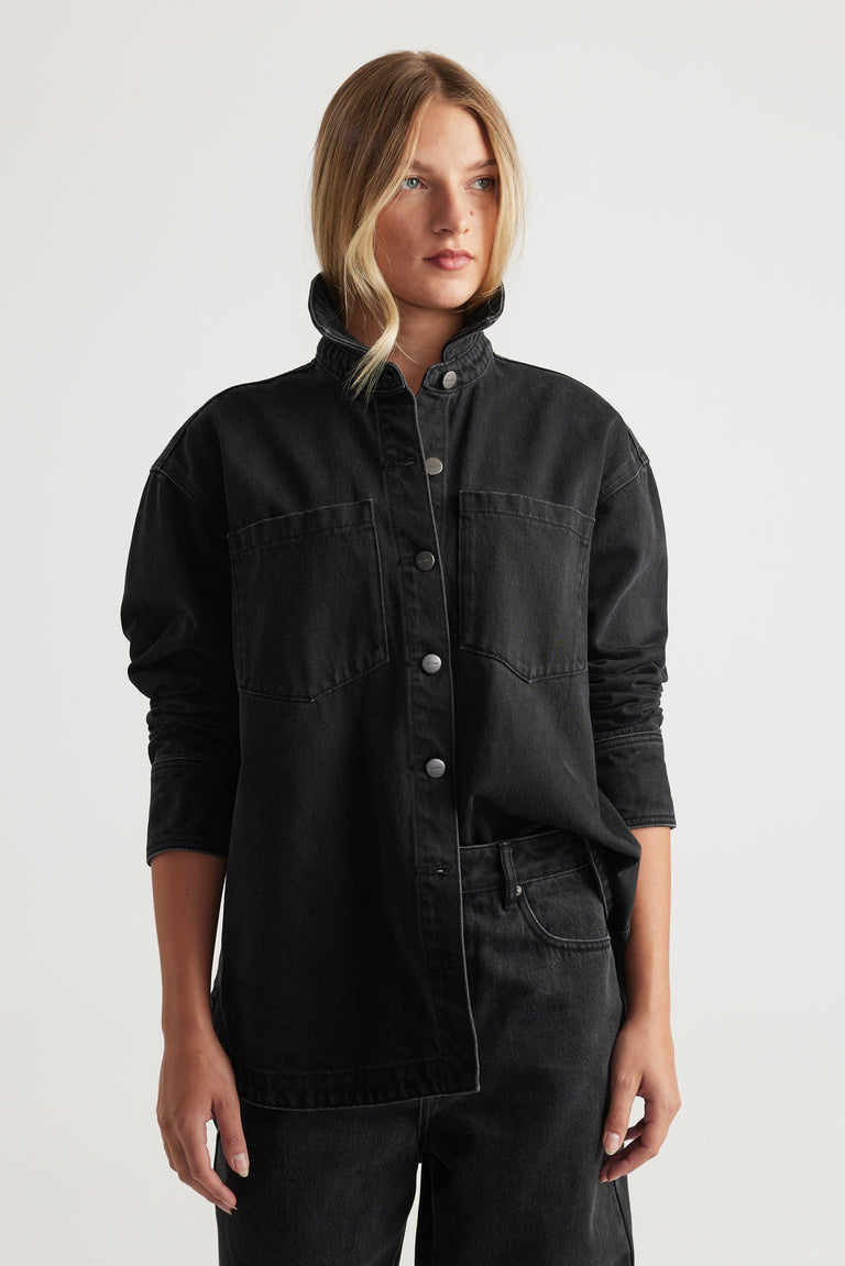 Woman wearing black denim shirt with snap buttons and chest pockets paired with black denim jeans for a modern casual look