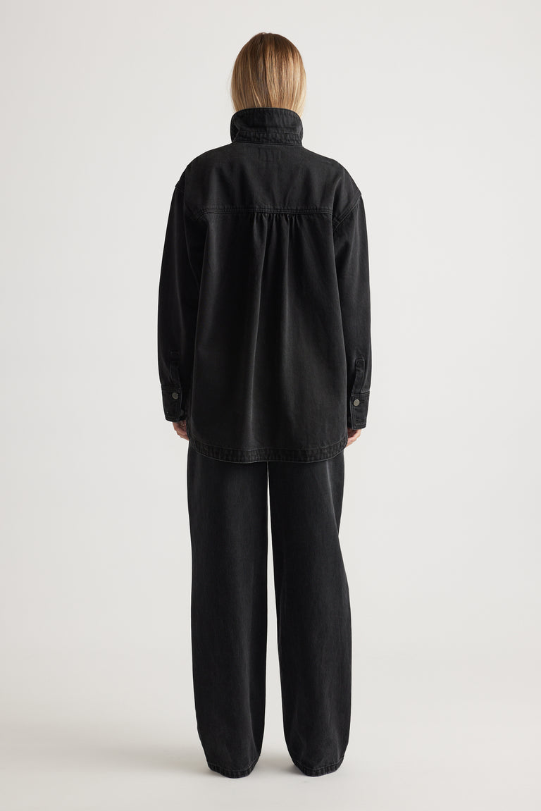 Woman seen from behind wearing an oversized black denim shirt paired with loose black wide-leg pants