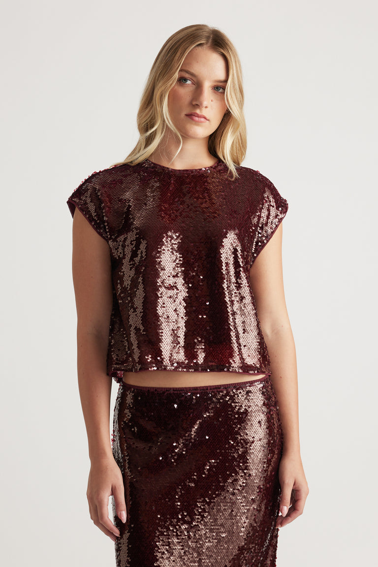 Woman wearing a plum sequin shell top with a relaxed fit, styled with a matching sequined skirt for a striking look