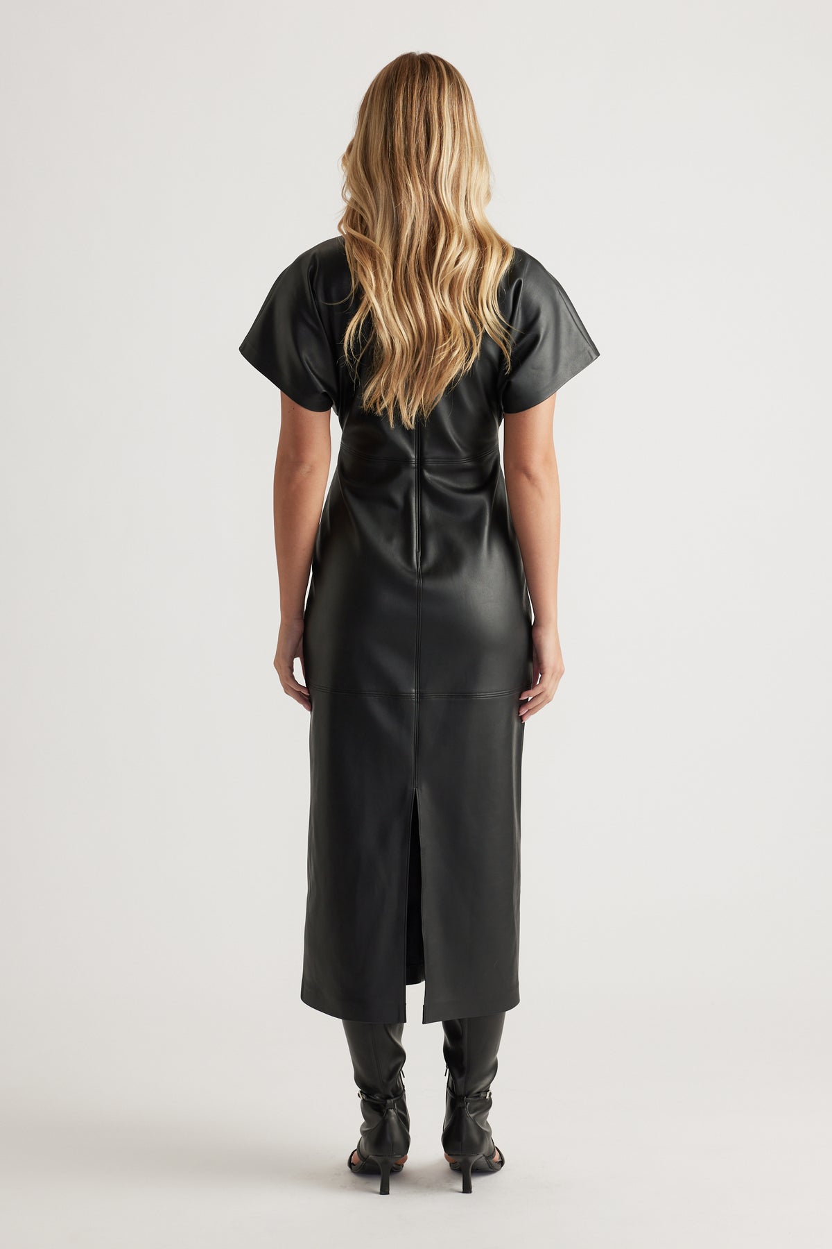 Back view of a fitted black faux leather midi dress with short sleeves and center back seam detailing.