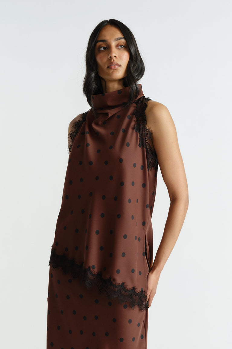 Woman wearing a brown halter top with black polka dots and delicate lace trim, styled for an elegant, effortless look