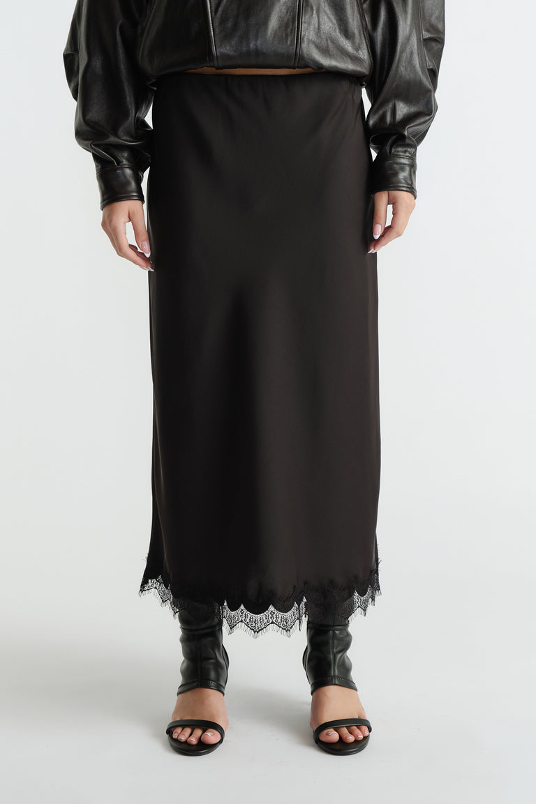 Black midi skirt featuring delicate lace trim at hem, styled with a cropped leather jacket and open-toe heels.