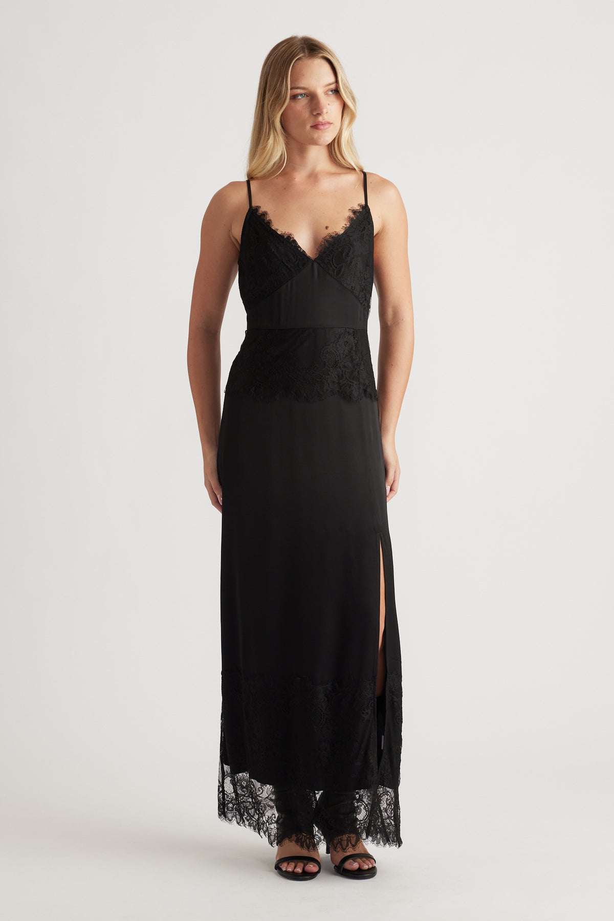 Black maxi dress with lace details, thin straps, a side slit, and a flattering fitted silhouette for evening wear