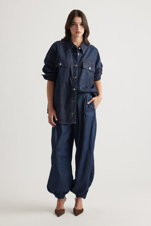 Woman wearing oversized dark denim shirt with large pockets and relaxed cuffed denim pants styled with brown heels