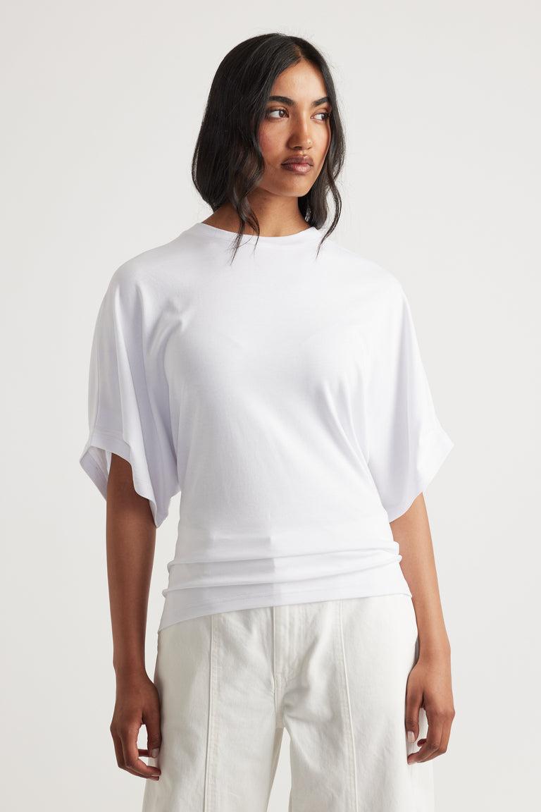Soft white tee with loose draped sleeves and a relaxed fit, paired with high-waisted light trousers