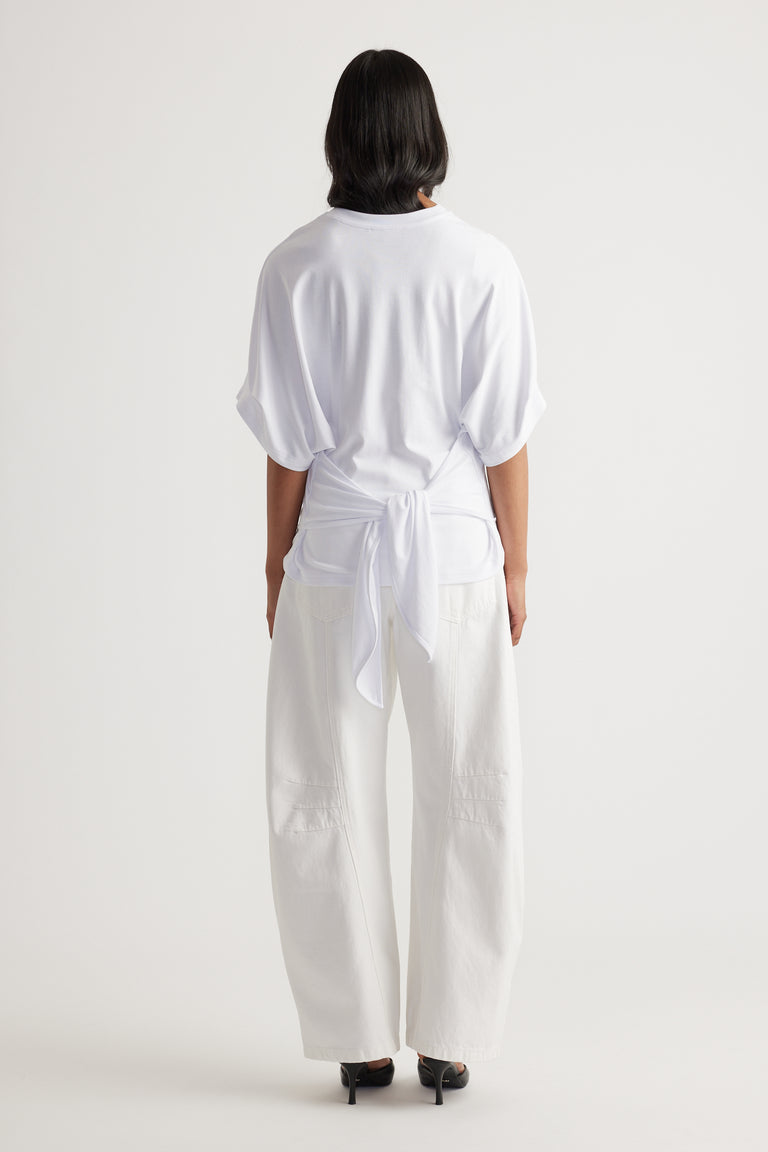 Back view of a relaxed white tie-back tee paired with wide-leg white pants and black heels for a modern look