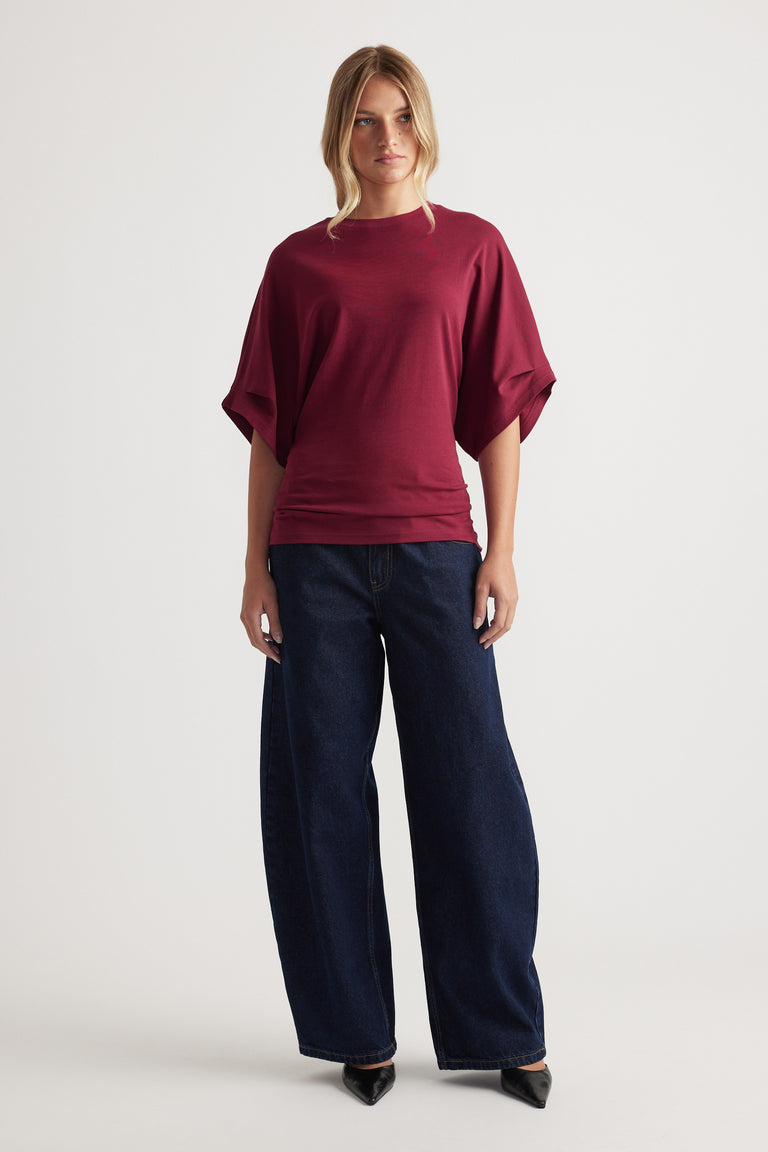 Loose fit burgundy tee with wide sleeves paired with high-waisted wide-leg dark denim jeans and pointed black shoes