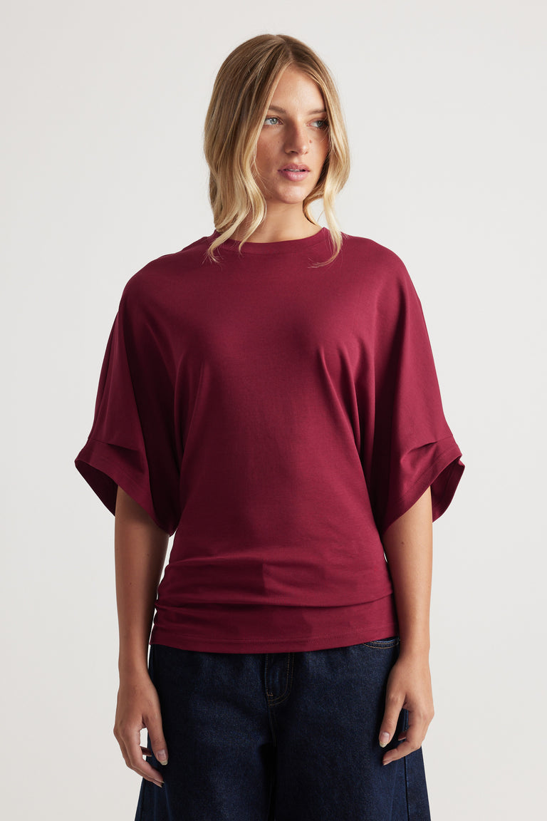 Relaxed fit deep red tee with wide short sleeves and a simple crew neckline paired with dark denim jeans