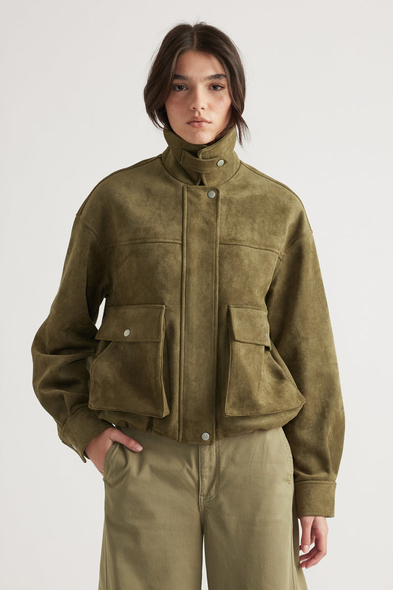 Olive green faux suede jacket with high collar and large flap pockets, styled for a relaxed yet chic look.