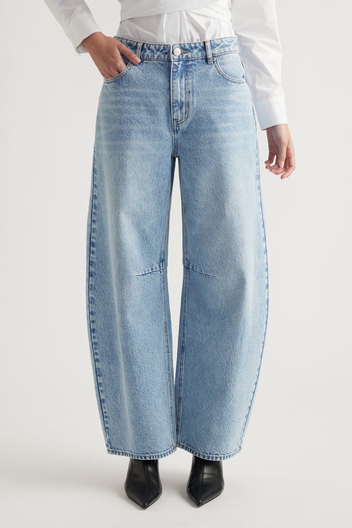 Woman wearing light blue wide-leg denim jeans paired with black pointed boots and a white shirt